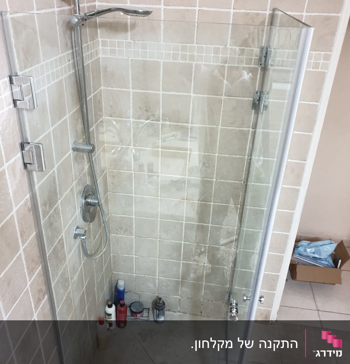 מקלחון עם בקבוקי שמפו וסבון על הרצפה